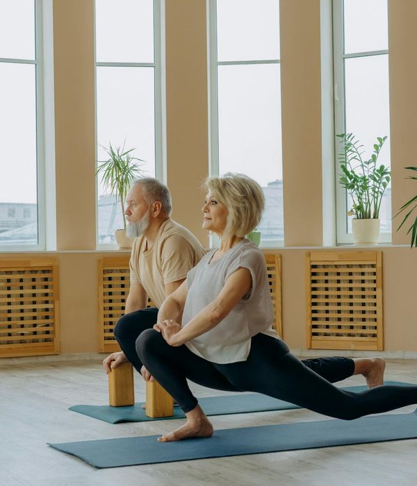 Woman performing a gentle back-stretching yoga pose indoors.